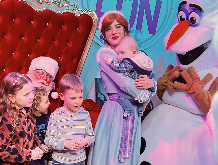 Santa greeting children at a holiday photo line in Metro Detroit while an Elf handler helps guests get camera ready.